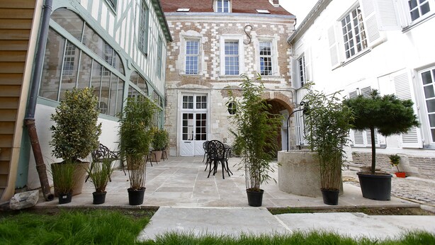 Un patio con piso de piedra, plantas en macetas y mobiliario exterior.