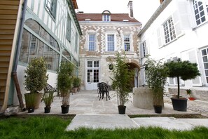 A courtyard with a stone floor, potted plants, and outdoor furniture. - Appart'Hotel Hotel Saint Georges (Troyes)