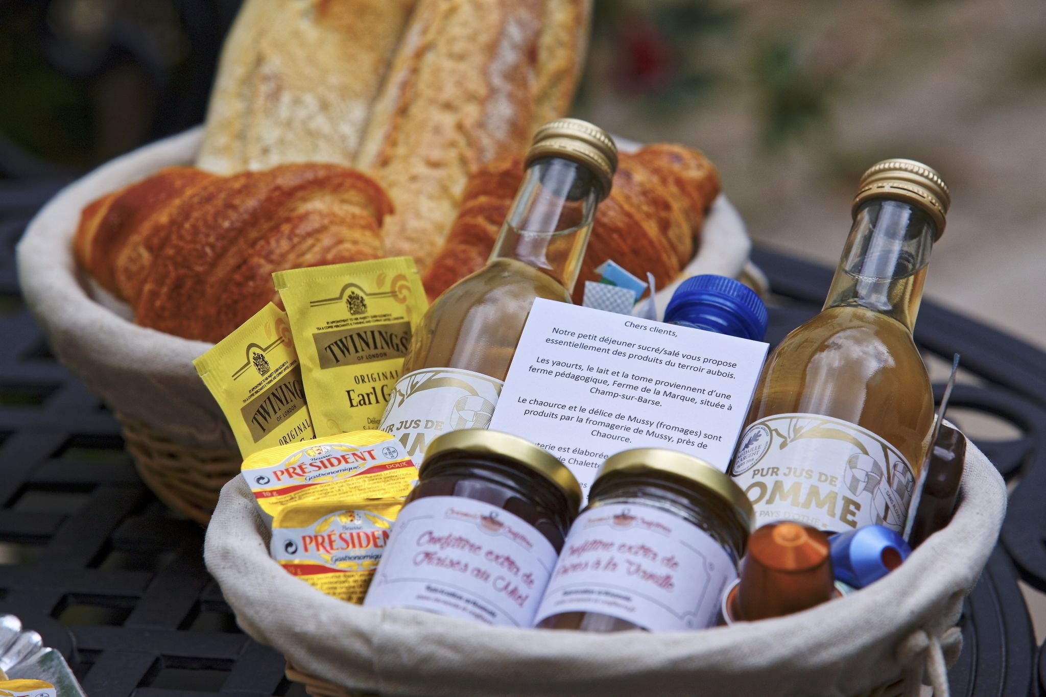 Ein Korb mit verschiedenen Lebensmitteln und Flaschen, darunter Brot, Gläser mit Marmelade und Weinflaschen.
