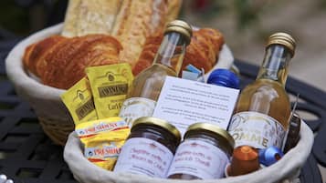 Ein Korb mit verschiedenen Lebensmitteln und Flaschen, darunter Brot, Gläser mit Marmelade und Weinflaschen.