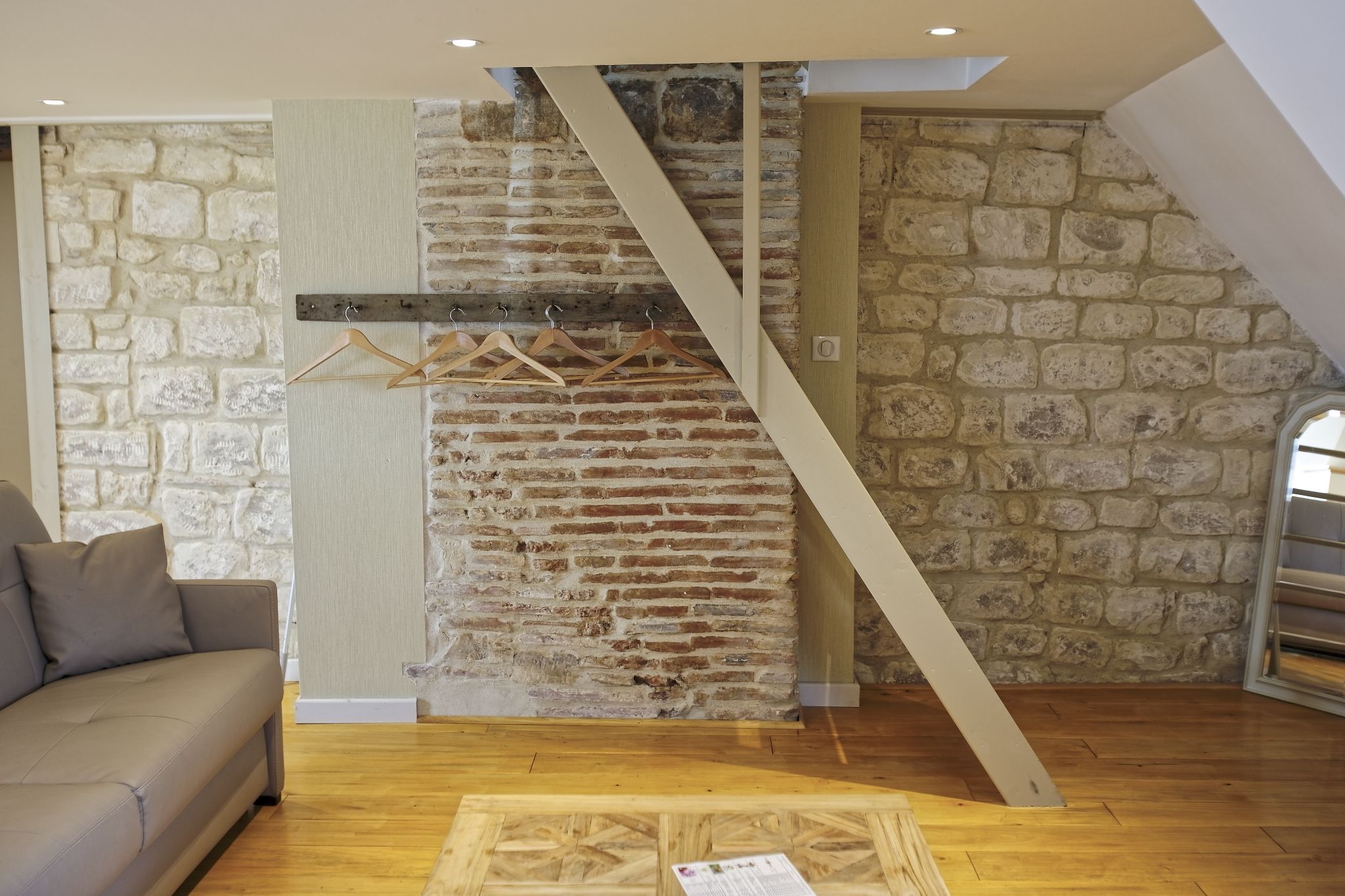 Ein Zimmer mit einer Steinsäule, einer Holztreppe, einem Sofa und Holzboden.