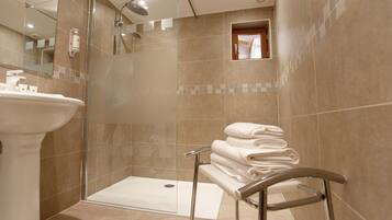 A modern bathroom with a glass-enclosed shower, a pedestal sink, and a towel rack.