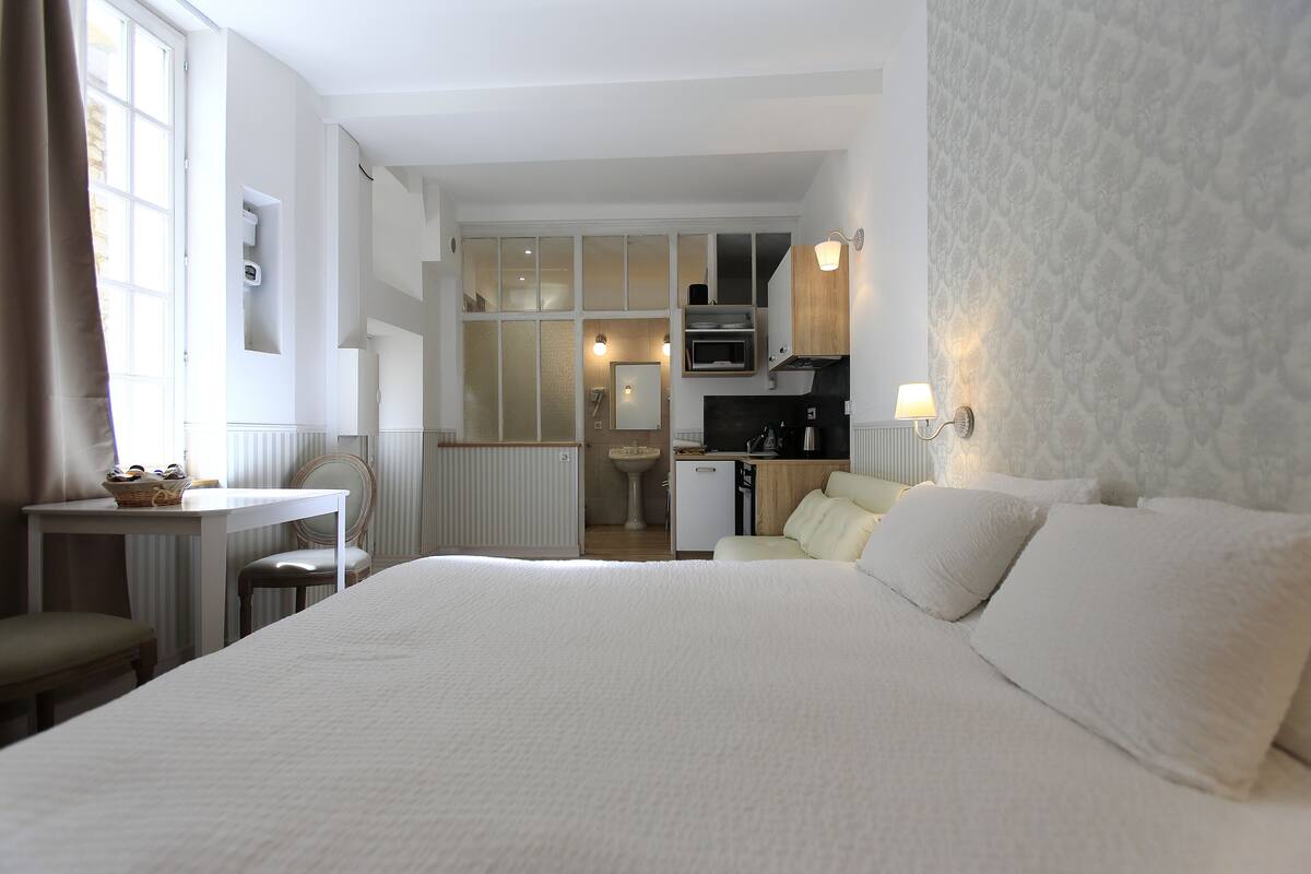 Een hotelkamer met een groot bed, een kleine kitchenette, een badkamer en een eethoek.