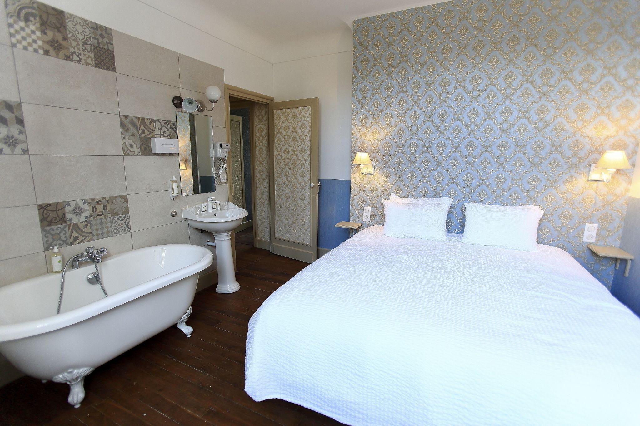 A room with a large bed, a bathtub, and a sink.