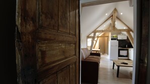 Una puerta de madera rústica que da a un cuarto con techo estilo loft, un sofá y una mesa.