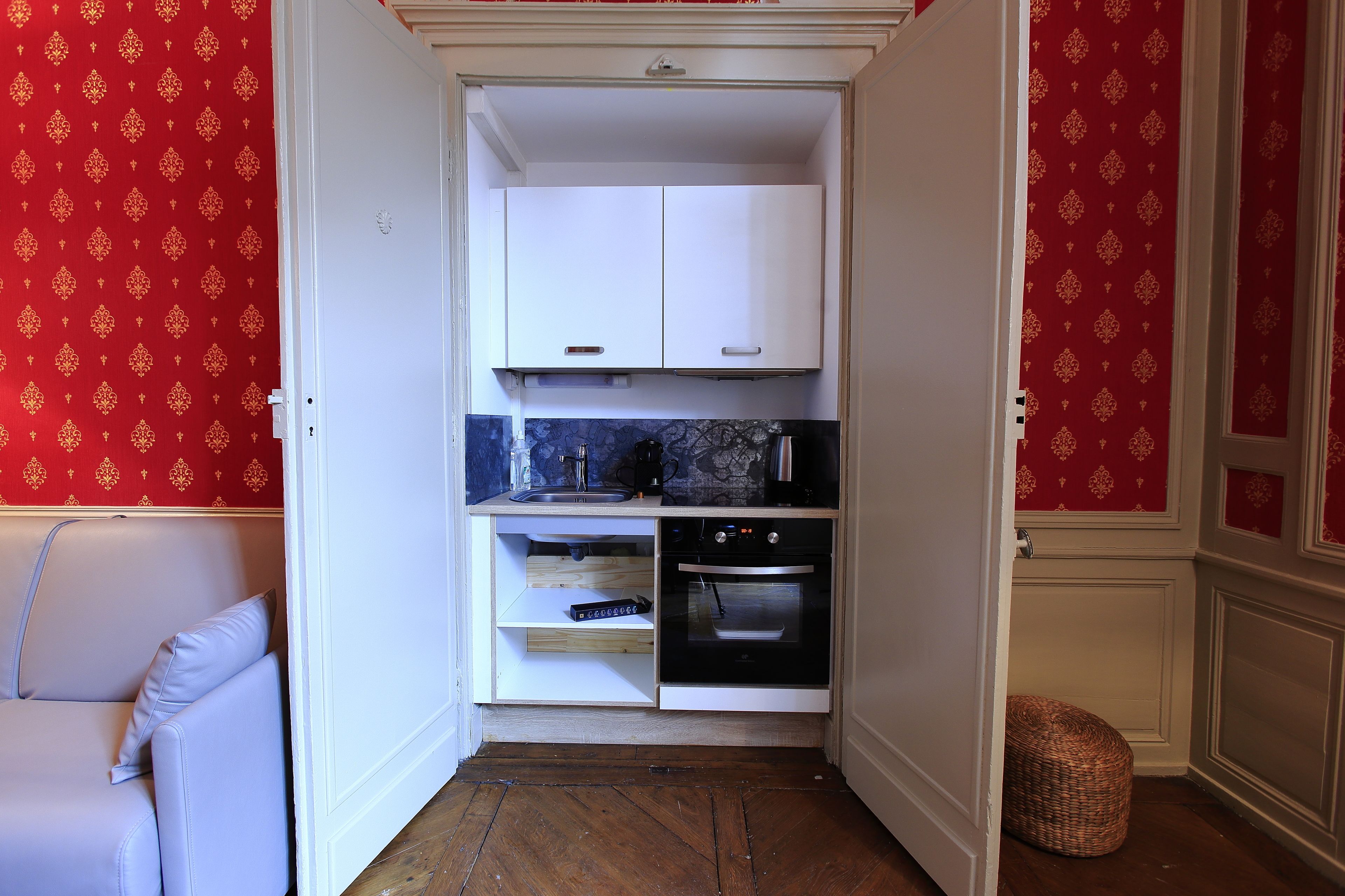 A compact kitchen with white cabinets, a built-in oven, and a wooden countertop.