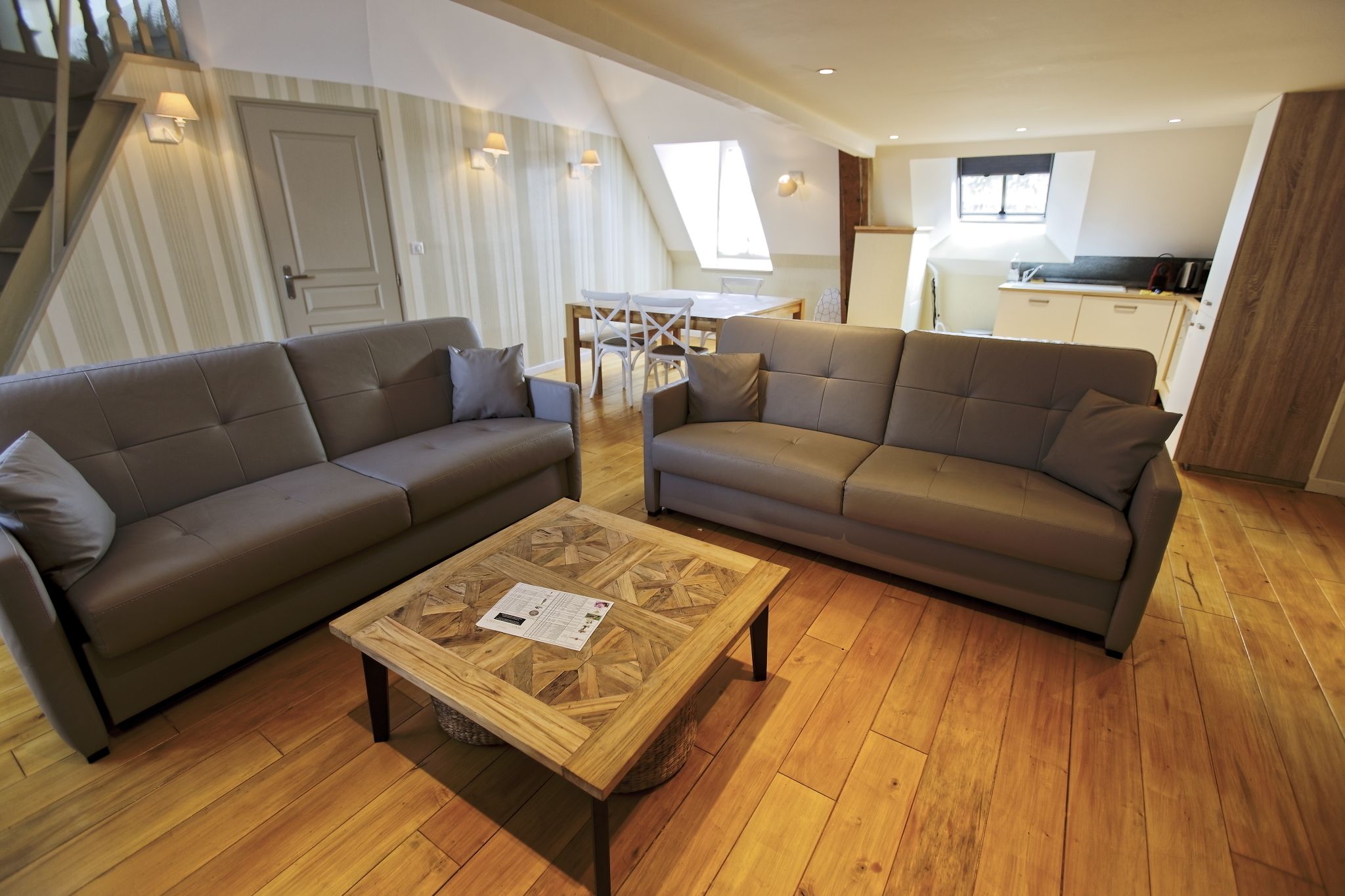 Ein modernes Wohnzimmer mit zwei Sofas, einem Couchtisch und einem Essbereich.