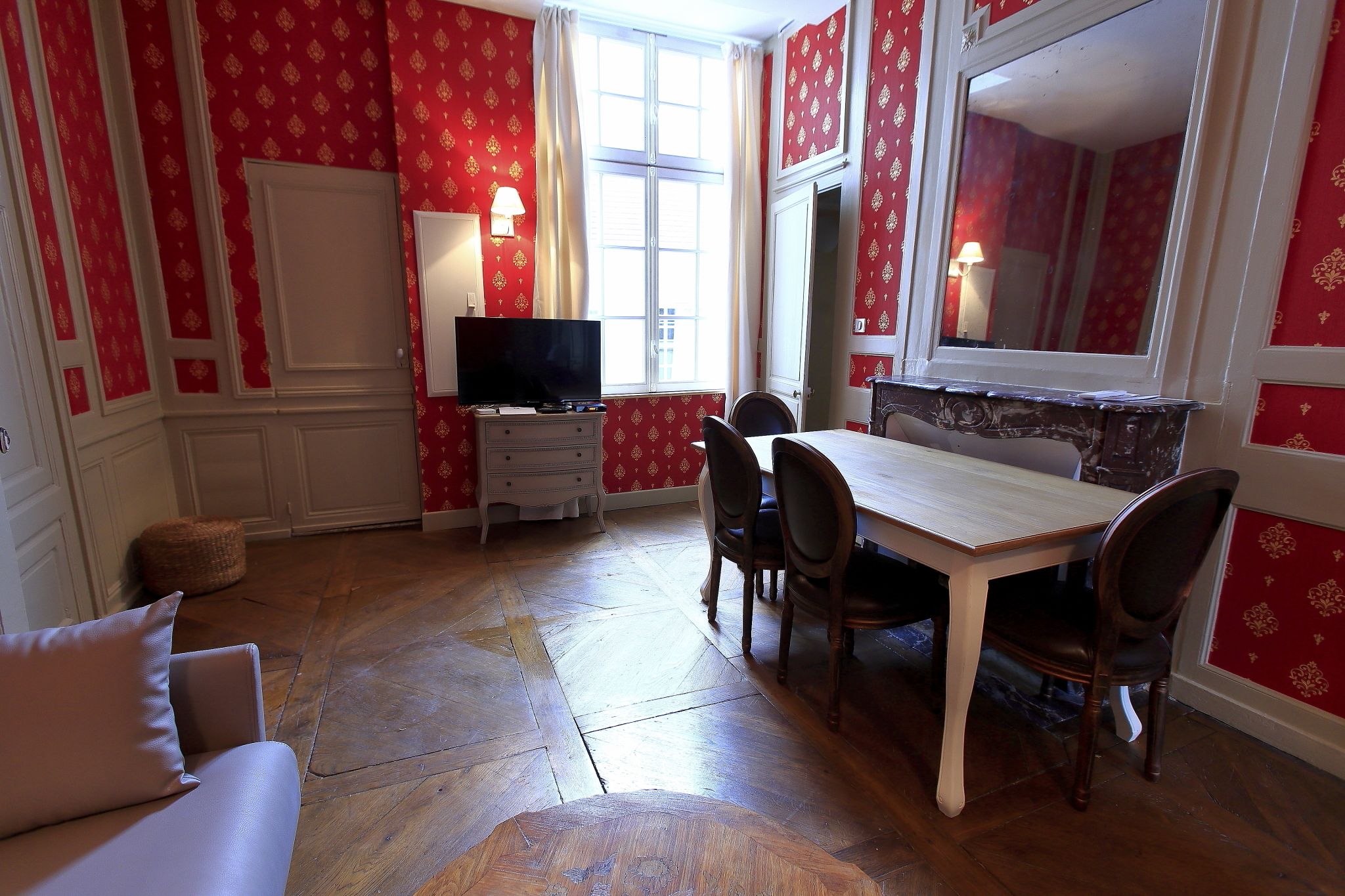 Una habitación con una mesa de comedor, sillas, un televisor y un espejo.