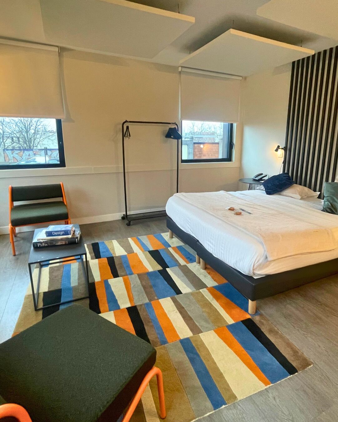 Une chambre à coucher moderne avec un lit, une chaise, une petite table et une fenêtre.