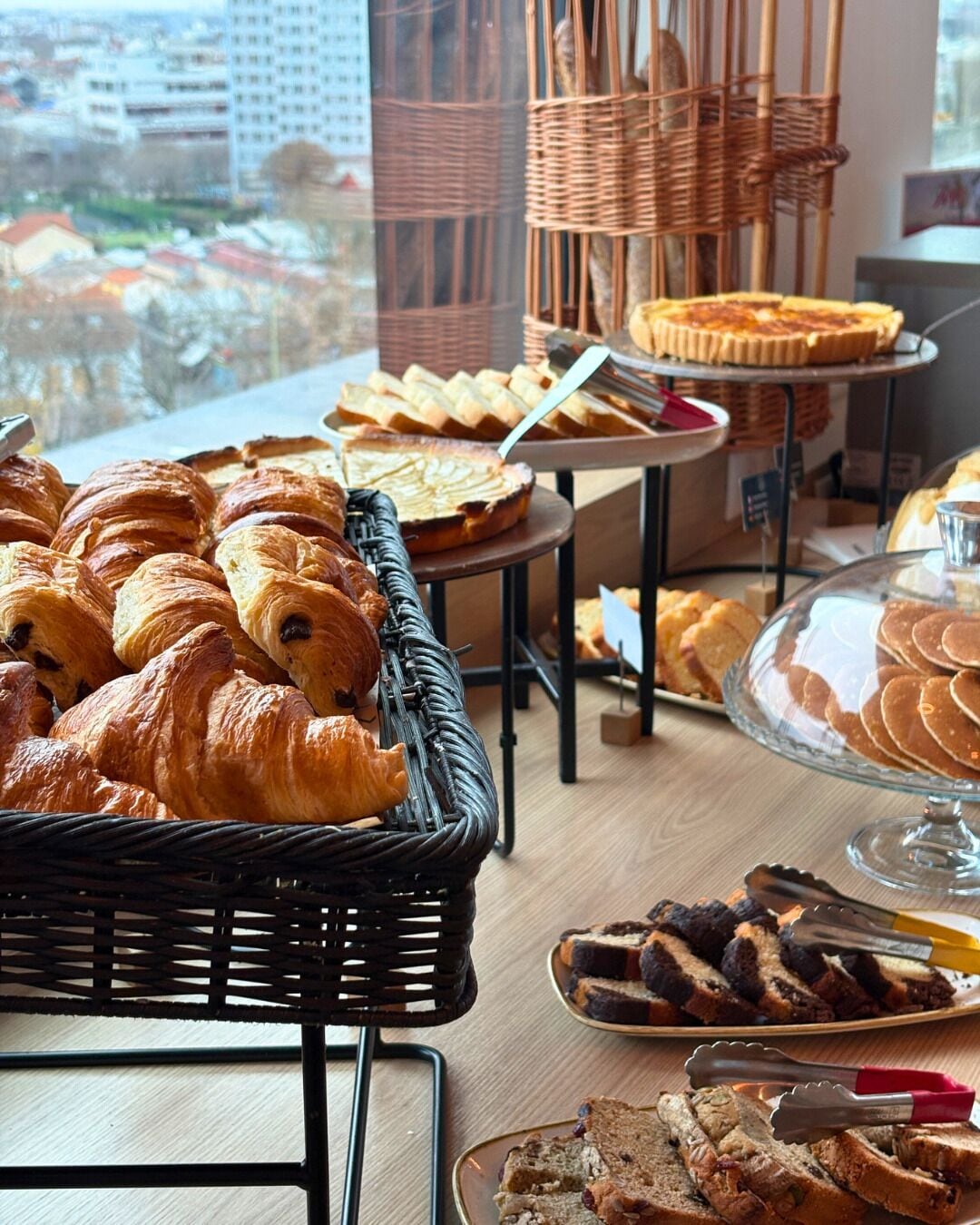 A buffet with various baked goods, including croissants and pies, arranged on tables and in baskets.