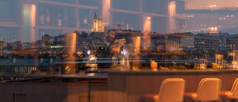 A bar with high stools and a cityscape view in the background.