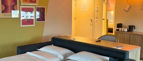 A double bed with a headboard, a bedside table, a mirror, and a small cabinet.