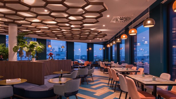 A modern restaurant with hexagonal ceiling lights, round tables, and chairs. - The Originals Boutique, Hôtel Maison Montmartre Paris Les Puces (Paris)