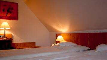 A hotel room with two beds, a wooden headboard, a nightstand with a lamp, and a painting on the wall.