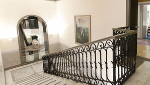A polished interior with a marble staircase, a decorative railing, and a framed artwork on the wall. - Hotel San Remo (Rome)