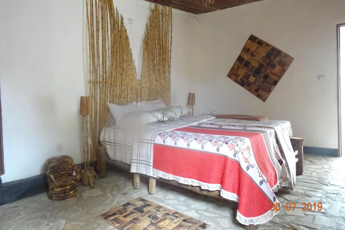 Ein Schlafzimmer mit einem Bett, einem Wandteppich, einer gewebten Matte und einem hölzernen Kopfteil.