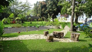 Un jardín bien cuidado con un sendero de piedra, abundante vegetación y un coche azul estacionado cerca.