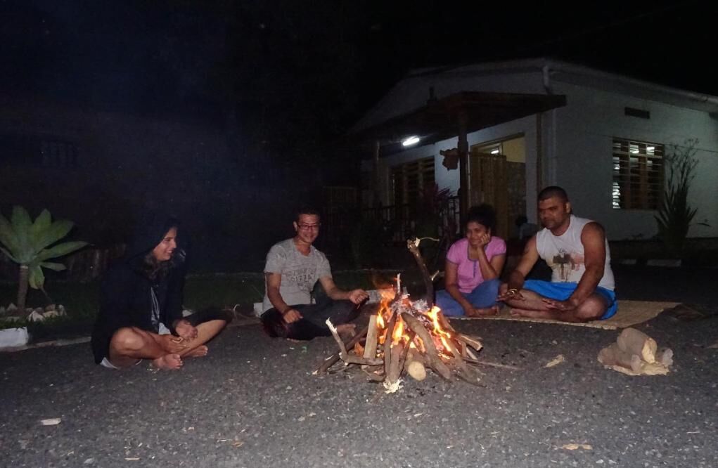 Vier Personen sitzen nachts im Freien am Lagerfeuer.