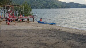 Una playa con un columpio y un barco llamado "SEVEN STARS" amarrado.