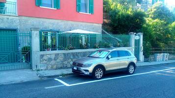 A beige SUV parked on a street with a stone wall and a metal gate in the background.