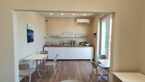 Una cocina compacta con armarios blancos, un comedor con dos sillas y un ventanal que proporciona luz natural.