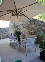 Un patio exterior con dos sillas, una mesa y un paraguas grande.