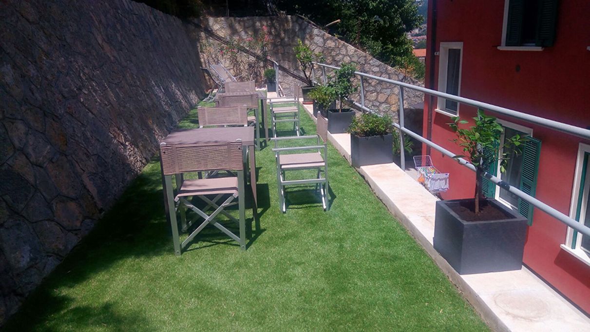 A patio with outdoor furniture, a stone wall, and a red building in the background.