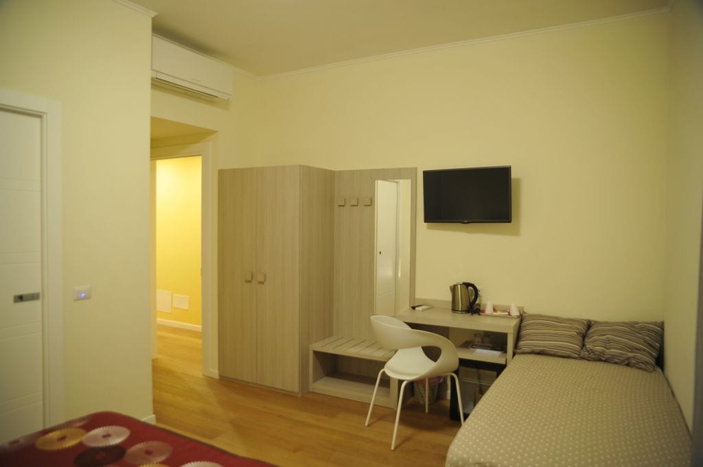Ein Schlafzimmer mit Bett, Schreibtisch, Stuhl, Fernseher und Kleiderschrank.