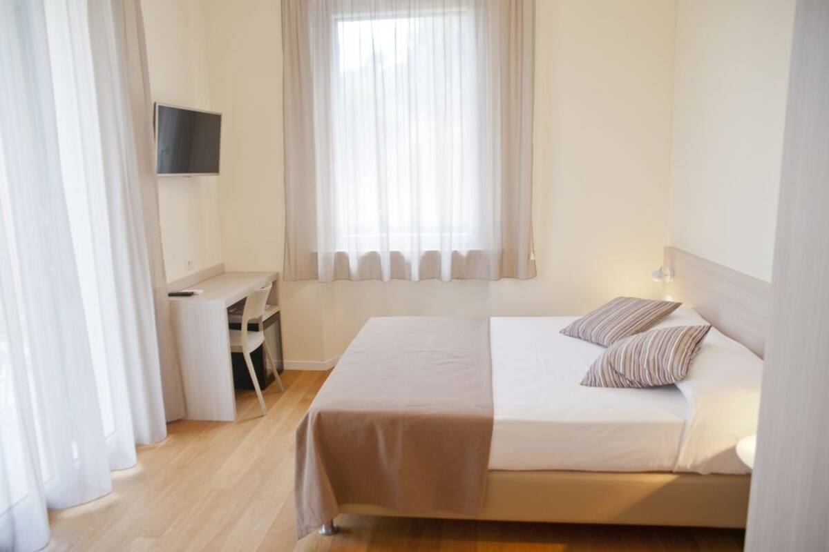 Una habitación de hotel con cama, escritorio y televisor.