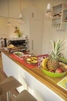 Una encimera de cocina con alimentos para el desayuno, una cafetera y bombillas colgantes.