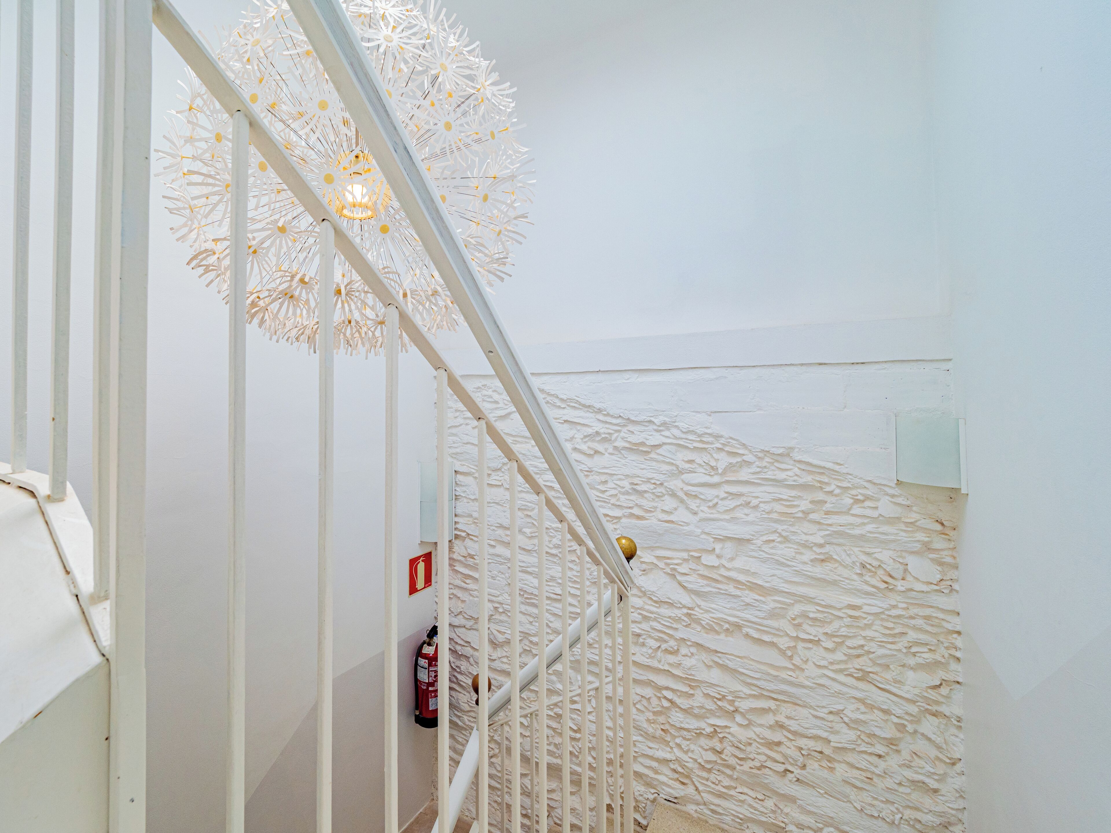 A staircase with white railings and a textured wall.