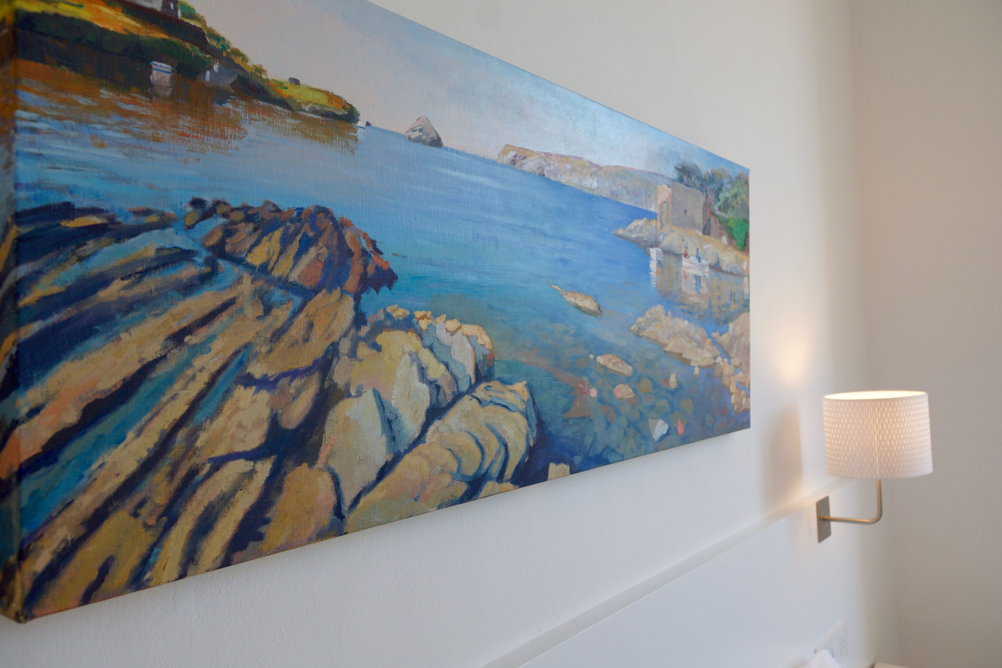 A painting of a coastal landscape on a wall.
