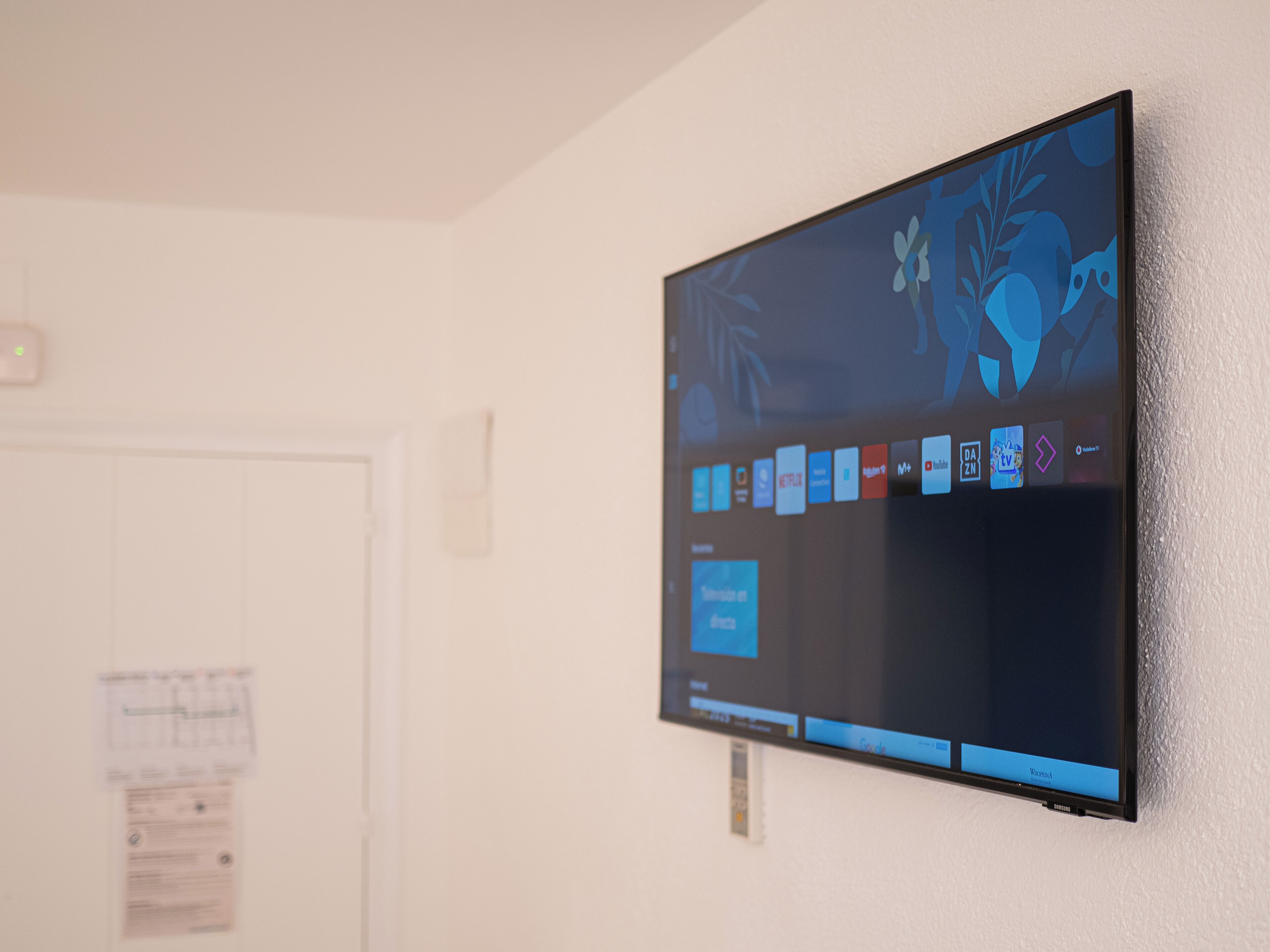Televisor de pantalla plana montado en la pared mostrando varios iconos de aplicaciones.