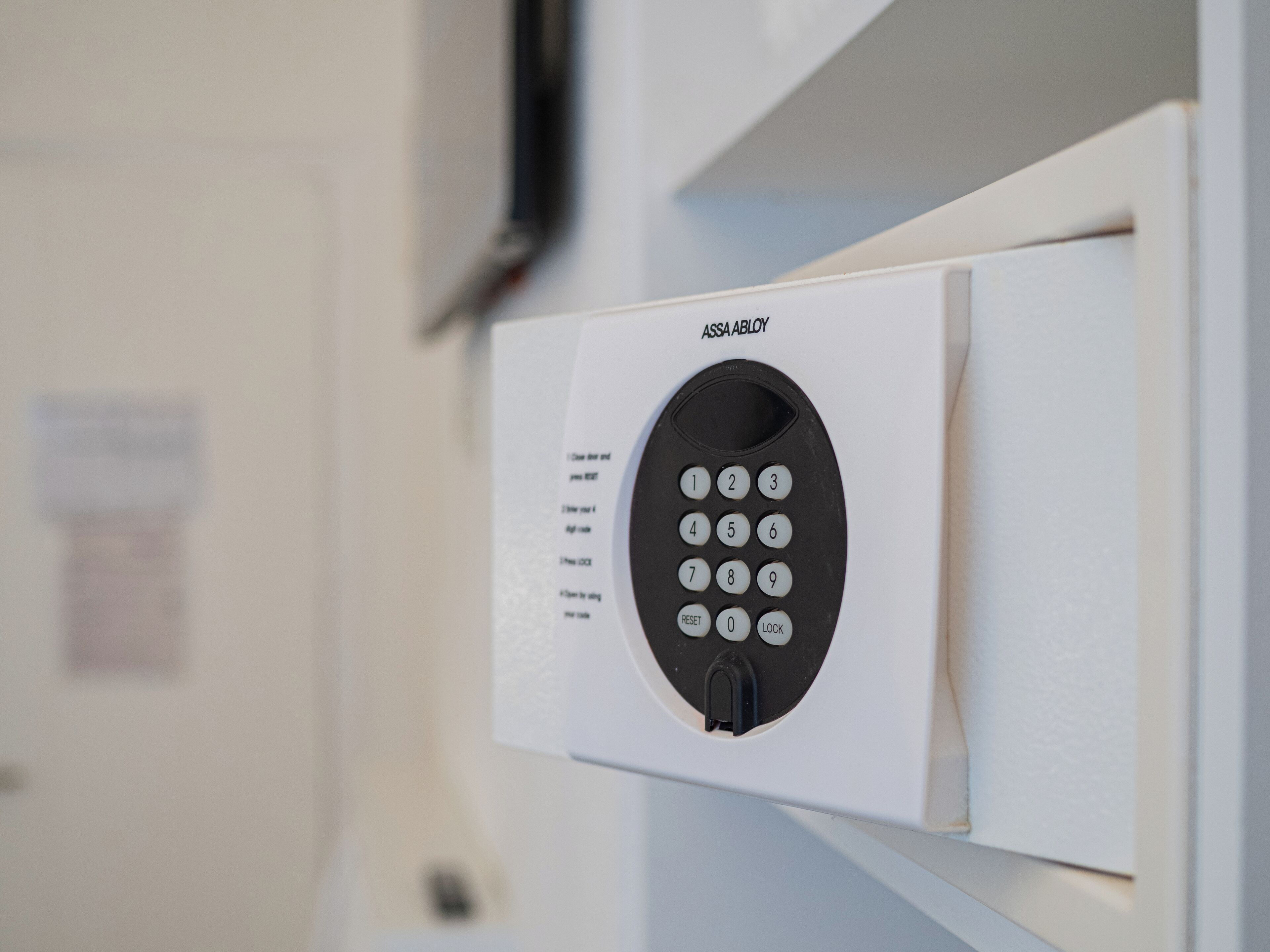 Een aan de muur bevestigd beveiligingspaneel met numeriek toetsenbord en een knop voor de vergrendeling.