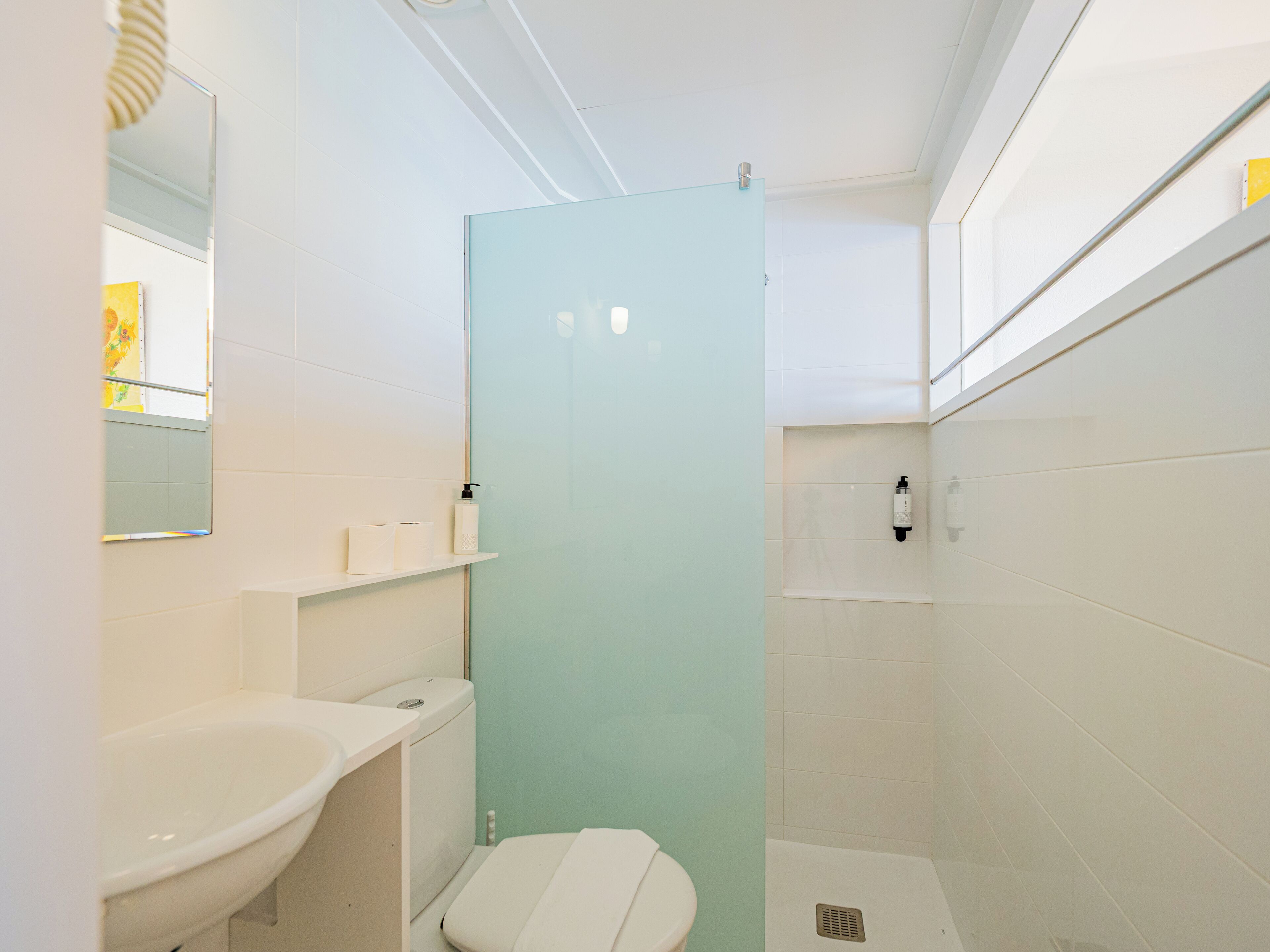 Ein kleines Badezimmer mit Waschbecken, Toilette und Duschkabine aus Glas.