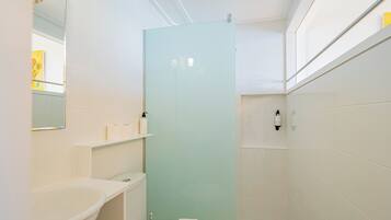 Un baño pequeño con lavamanos blanco, inodoro y cabina de ducha de vidrio.