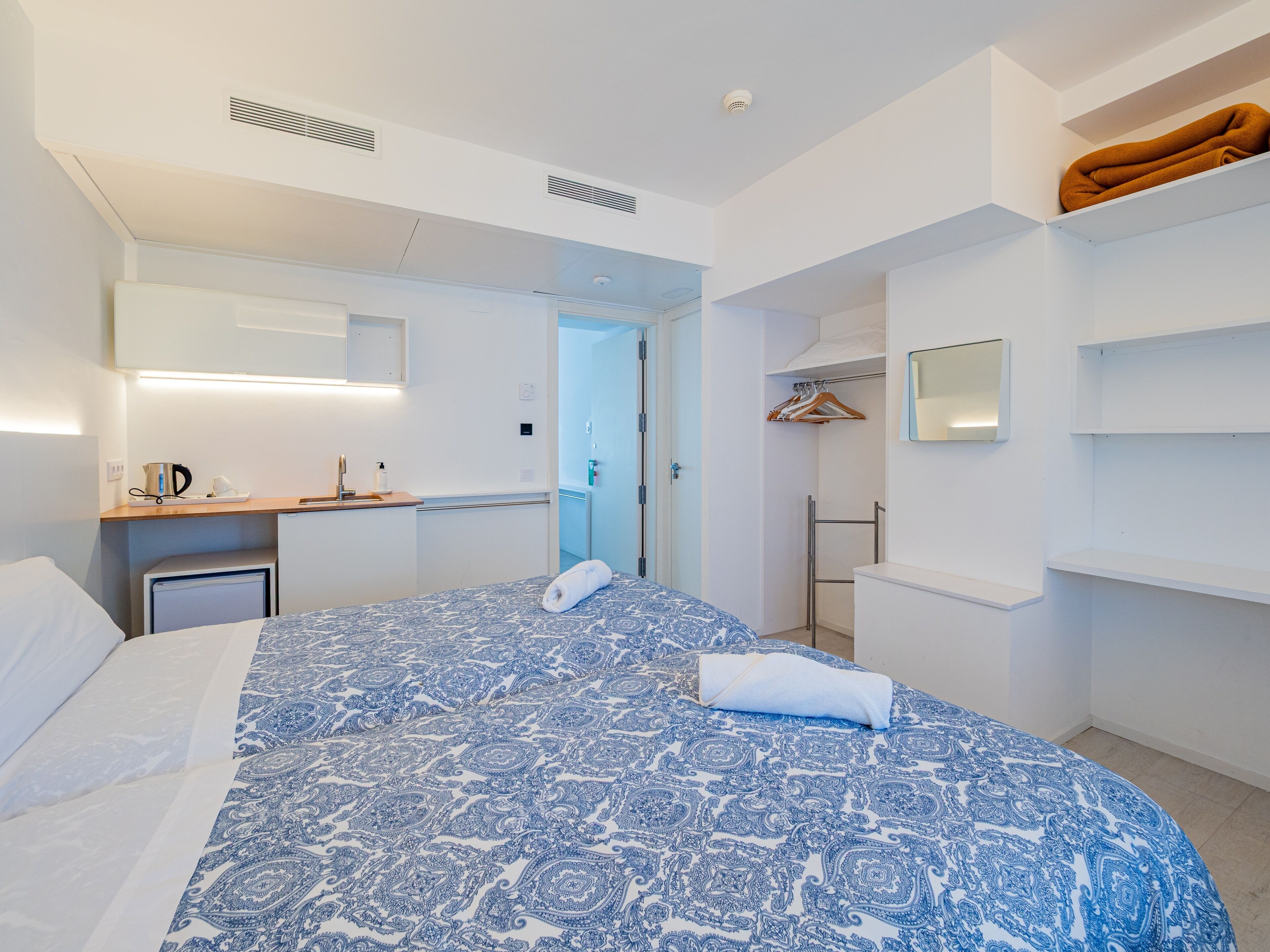 Camera d'albergo con un letto grande, un comodino con un bollitore, uno specchio, un armadio e una zona doccia.