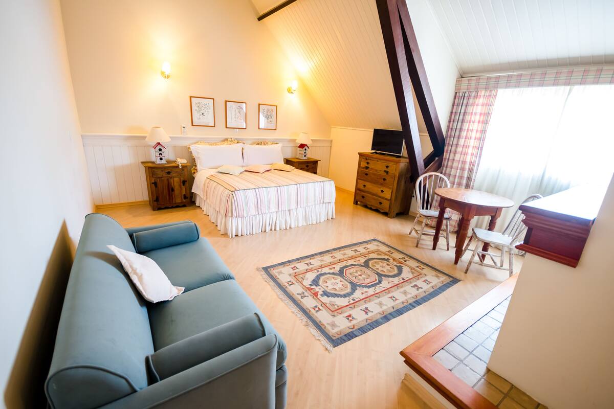 Ein gemütliches Zimmer mit Bett, einer Couch, einem kleinen Tisch und einem Fernseher.