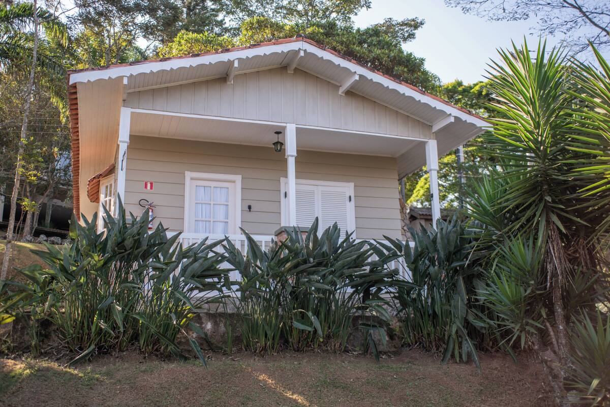 Ein bungalowartige Haus mit Veranda, umgeben von tropischer Bepflanzung.