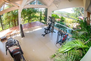 Uma academia com equipamento de exercícios e vista para um jardim bem cuidado.