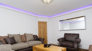 A living room with a sofa, armchair, and coffee table. - Sycamore House (Leeds)