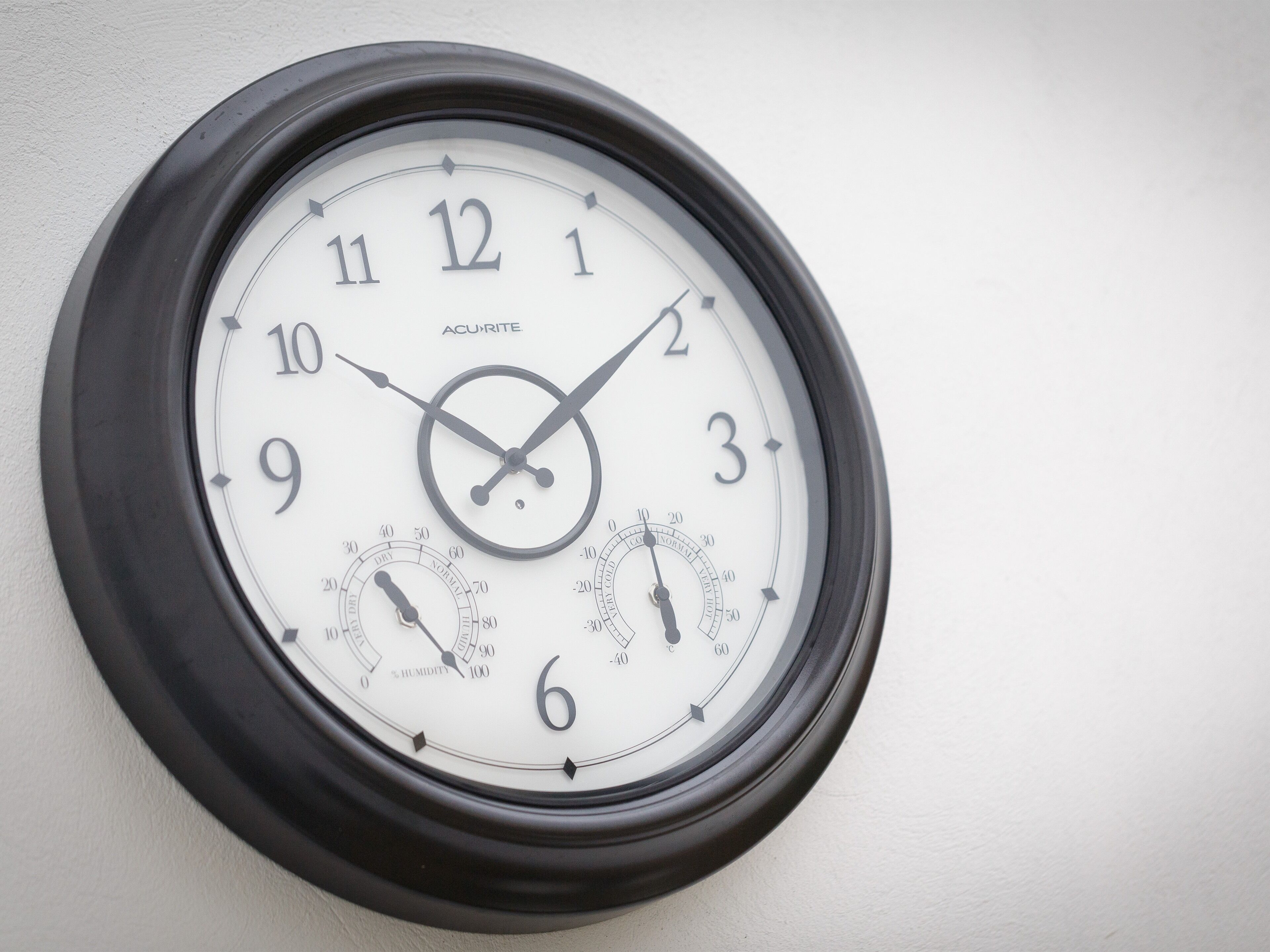 Une horloge murale dotée de plusieurs cadrans, notamment un affichage de l’heure classique et des cadrans supplémentaires indiquant l’humidité et la température.