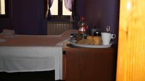 A hotel room with a bed, a small table with breakfast items, a window with curtains, and a radiator. - Macci Art (Florence)