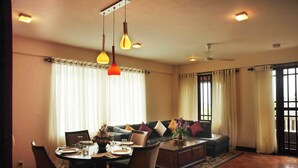 A dining area with a round table set for four, a sofa with cushions, and a coffee table with a plant. - The Prestige Court Residence (Mount Lavinia)