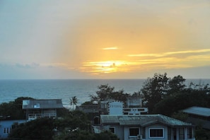 A coastal view with a sunset over the ocean, buildings with signage, and a clear sky. - The Prestige Court Residence (Mount Lavinia)