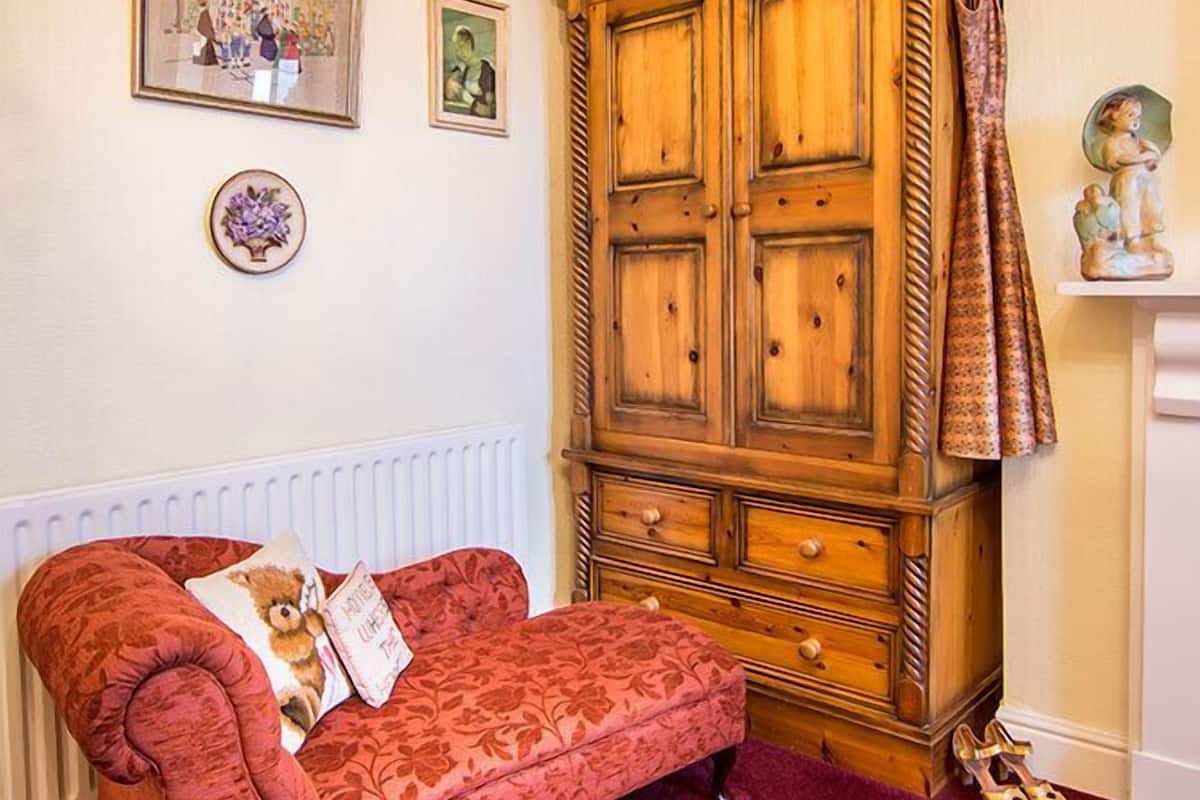 Une pièce avec un canapé en velours rouge, un meuble en bois et un radiateur.