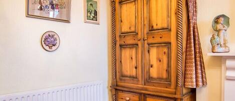 A room with a red velvet sofa, a wooden cabinet, and a radiator.