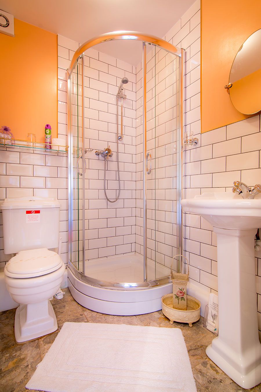 A bathroom with a glass-enclosed shower, a toilet, a sink, and a small decorative basket.