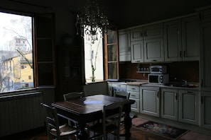 A kitchen with white cabinets, a wooden table, and a window overlooking a building.
