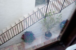 Una escalera con barandas de metal, plantas en macetas y vista del exterior de un edificio.